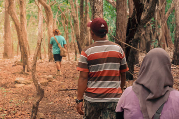 Rinca Island, Labuan Bajo, Flores, East Nusa Tenggara, Indonesia - June 13, 2016: Group of people, walking inside the forest, doing the trekking, encircle the Rinca island in Labuan Bajo